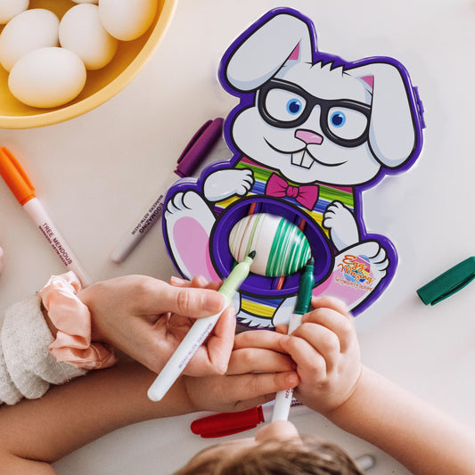 Bunny shaped egg decorator in use on table with markers being held to a blank egg